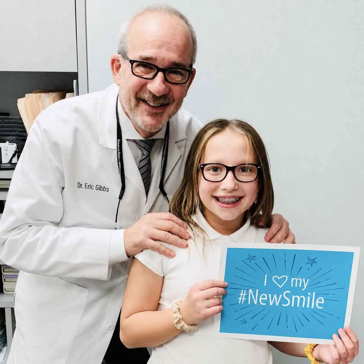 Dr. Gibbs with a young braces patient holding a My New Smile sign at Gibbs Orthodontic Associates on the Upper East Side of New York